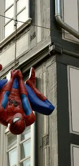 Spider-Man hanging upside down by a building, vibrant urban background.
