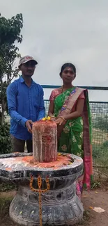 Couple performing ritual at Shiva Linga outdoors.