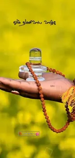 Hand holding lingam with beads on yellow background.