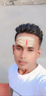 Young man with spiritual forehead marks taking a selfie.