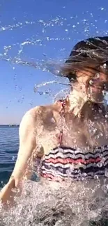 Woman splashing in the ocean under a clear blue sky.