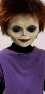 A spooky doll with dark eyes and a purple shirt stands on a plain background.