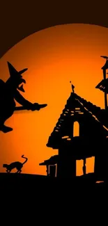 Witch flying over haunted house against a full orange moon.