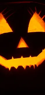 Glowing orange jack-o'-lantern with a spooky face on a dark background.