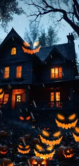 Haunted house with glowing pumpkins at night.