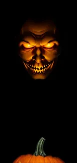 Dark wallpaper with glowing pumpkin and scary face.