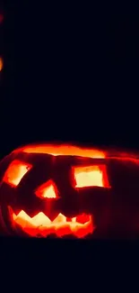 Glowing jack-o'-lantern against a dark background.