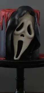 Spooky mask cake with dark eerie design on a stand.