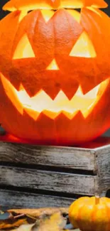 Glowing carved pumpkin on wooden crate with autumn leaves for Halloween.