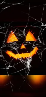 Spooky pumpkin face with spiderwebs on a Halloween-themed wallpaper.