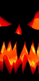 Spooky glowing pumpkin face mobile wallpaper with dark background.