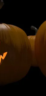 Spooky Halloween pumpkin wallpaper with glowing jack-o'-lanterns and dark background.