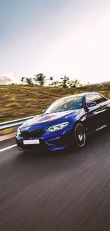 Blue sports car racing along a scenic road at sunset.