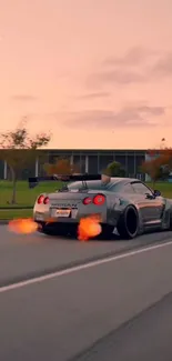Sportscar driving on road at sunset with fiery exhaust flames.