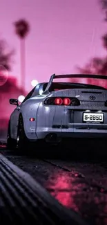 Sleek car under neon pink skies at dusk on a street.