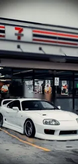 A sleek white car parked at a convenience store during the night.