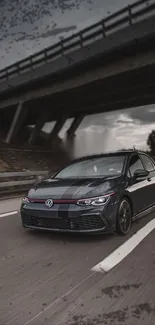 Sleek car driving under bridge on highway.