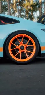 Sporty car with vibrant orange wheel parked.