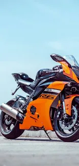 Orange sport motorcycle parked with blue sky background.