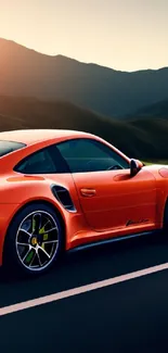 Orange sports car driving at sunset with a mountain backdrop.