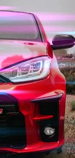 Sporty red car with neon lights in scenic background.