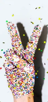 Colorful hand with sprinkles showing peace sign.