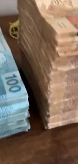 Stack of money on a wooden table with blue and beige notes.