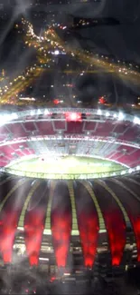 Aerial view of stadium lights glowing at night with cityscape beyond.