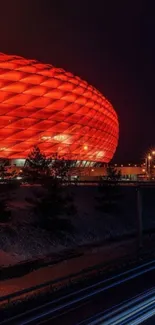 Red stadium glowing at night with light trails in foreground.