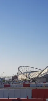 Panoramic view of a stadium and tower against a clear blue sky.