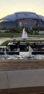 Stadium with a sunset view and water fountains in the foreground.