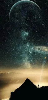 Lone figure on mountain under starry sky with galaxies shining.