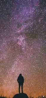 Silhouette gazing at a star-filled night sky with a purple Milky Way.