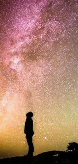 Silhouette of a person under the vibrant Milky Way with a purple night sky.