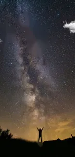 Silhouette under the starry Milky Way sky with vibrant cosmic colors.