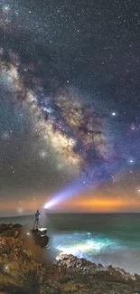 Person standing at night under the Milky Way, holding a light towards the starry sky.