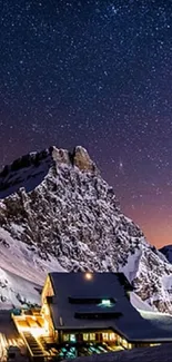 Snowy mountain and lodge under starry night sky wallpaper.