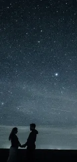 Silhouetted couple under a starry night sky.