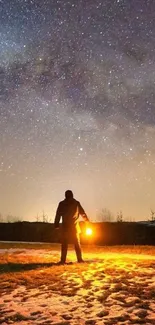 Silhouetted figure under a starry night sky holding a glowing light.