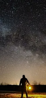 Silhouette against starlit night sky with lantern glow.