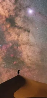 Person standing on sand dune under a starry galaxy filled sky.