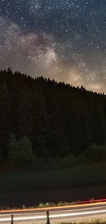 Starry night sky over a dark forest landscape.