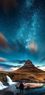 Mountain under starry night sky with waterfall.