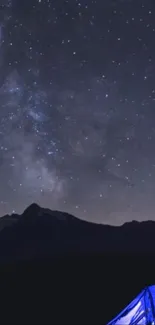 Camp under a starry mountain night sky with a glowing tent.