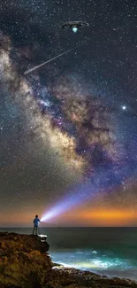 Person on cliff under starry sky with UFO and Milky Way.