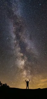 Silhouetted figure under Milky Way stars at night.