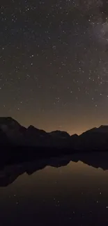 Starry night sky reflecting on a mountain lake in serene calmness.