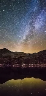 Starry night sky over mountain silhouettes with galaxy visible.