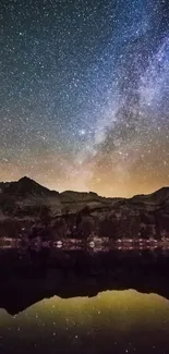 Starry night sky over mountains, reflecting in serene water.