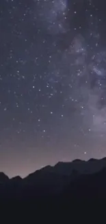 Starry night sky over dark mountain silhouette.